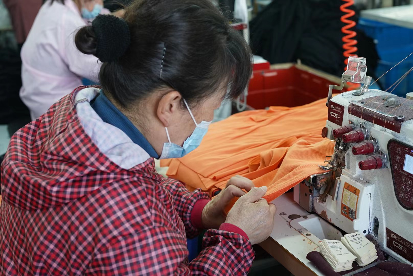 And here a ribbon is being set in the armholes of our orange mock-tops, to strengthen them and make them more comfortable to wear.